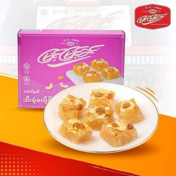 A magenta Myint Myint Khin gift box beside a plate of golden Htoe Mont squares topped with sliced almonds and sultanas